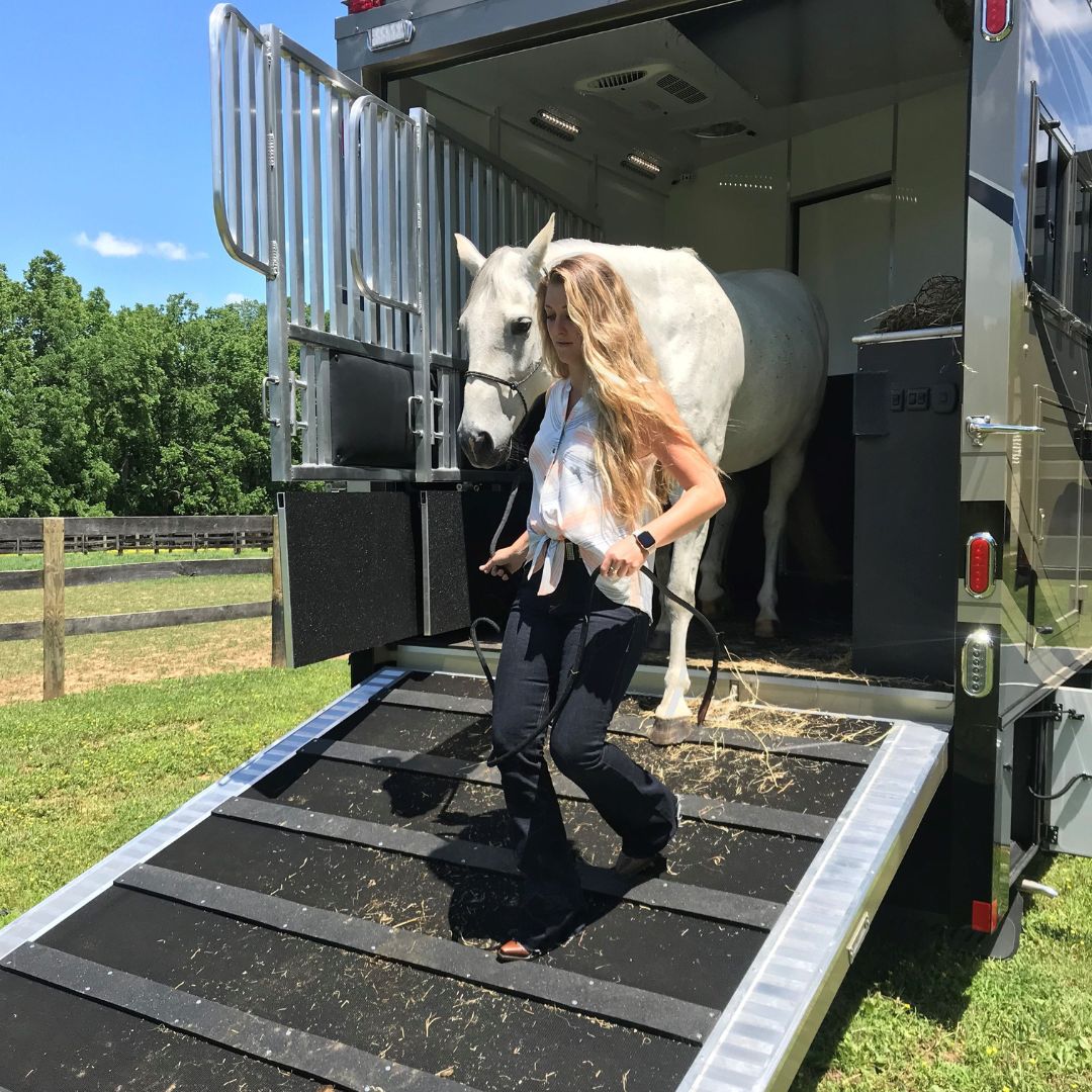 woman walking horse out of trailer