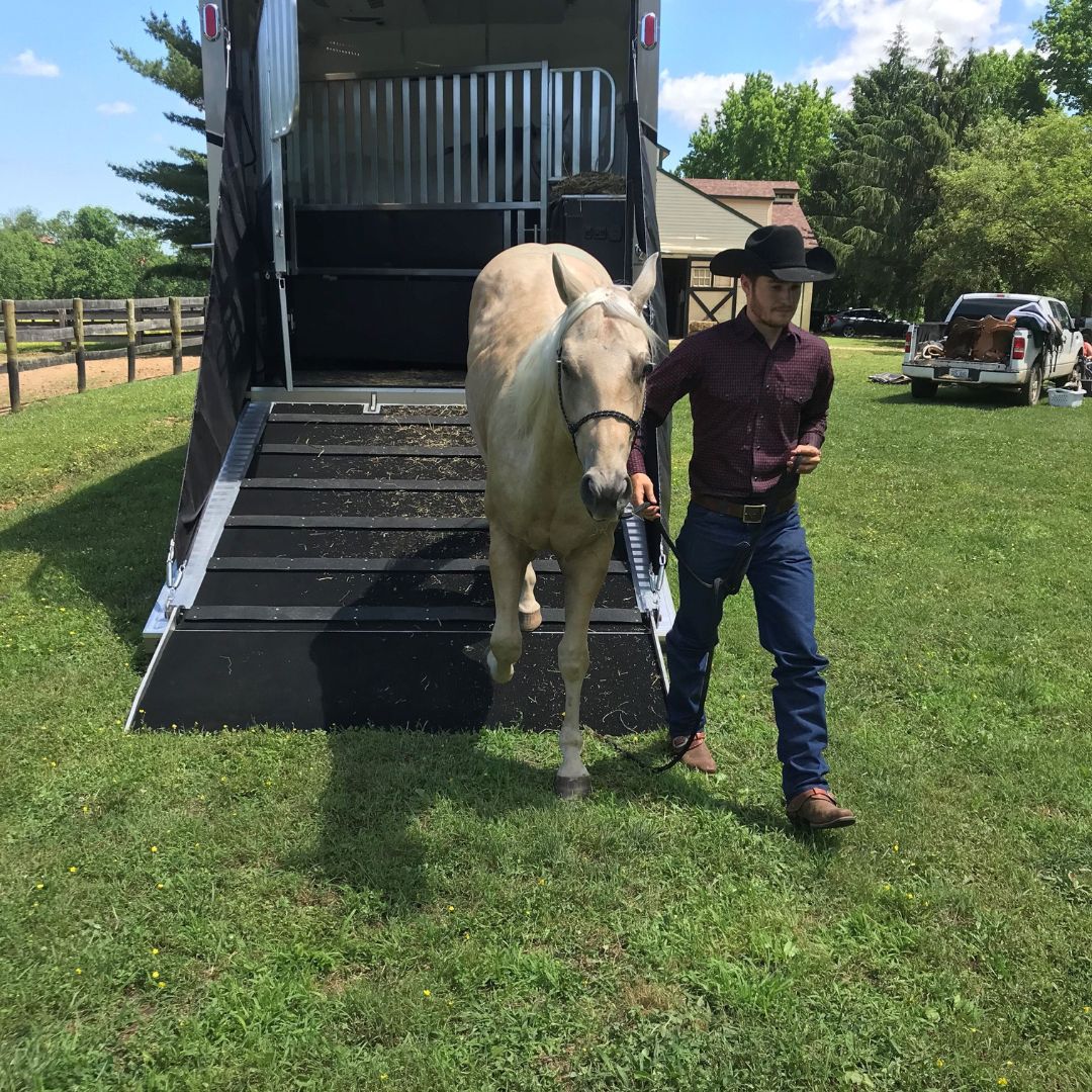 man walking horse out of trailer
